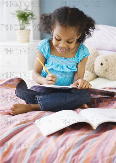 Mixed race girl doing homework in bedroom