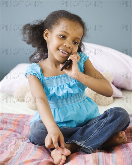 Mixed race girl in bedroom using cell phone