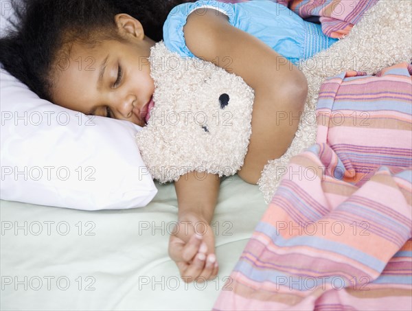 Mixed race girl sleeping with teddy bear