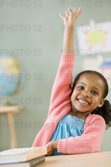 Mixed race girl raising hand to answer question