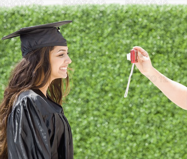 Middle Eastern woman in cap and gown having photograph taken