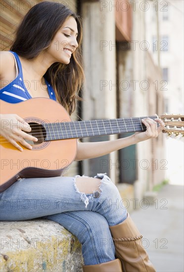 Middle Eastern woman playing guitar