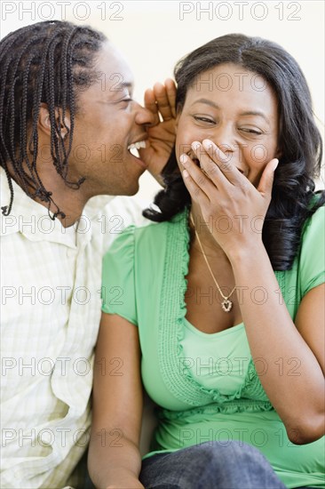 African man whispering in woman's ear