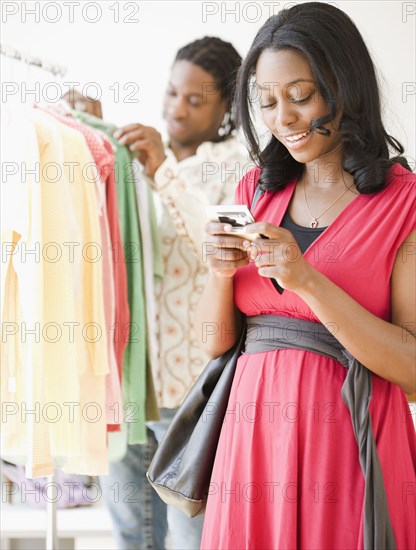 African woman text messaging on cell phone in shop