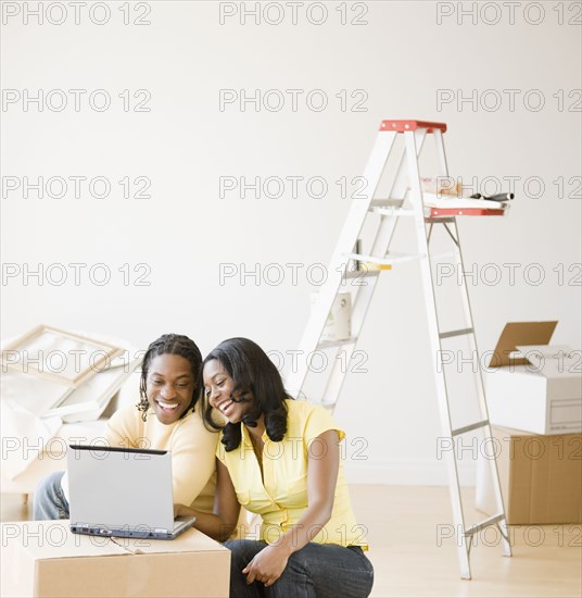 African couple on laptop with moving boxes