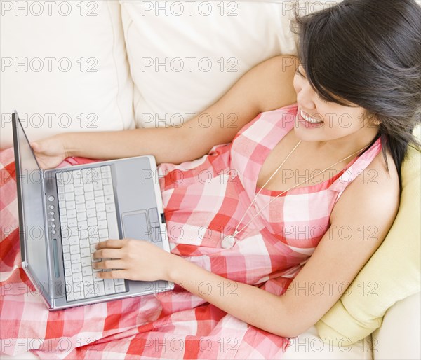 Asian woman using laptop on sofa