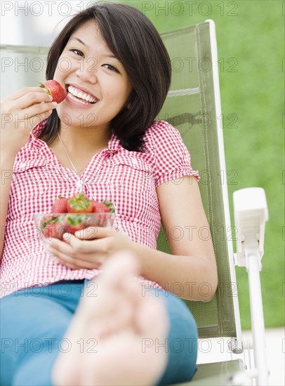 Asian woman eating strawberries