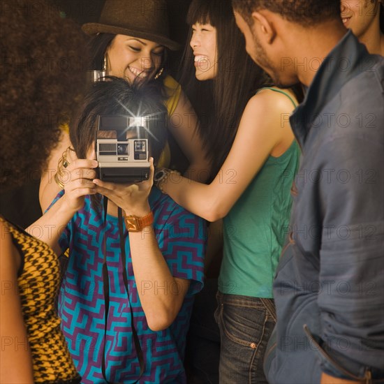 Asian man using instant camera in nightclub