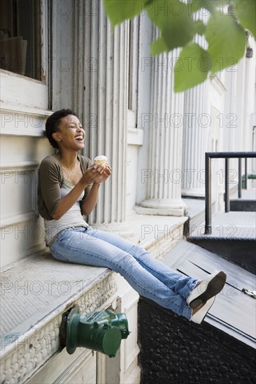 African woman eating cupcake outdoors