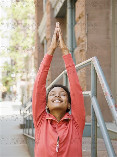 African woman stretching on urban sidewalk