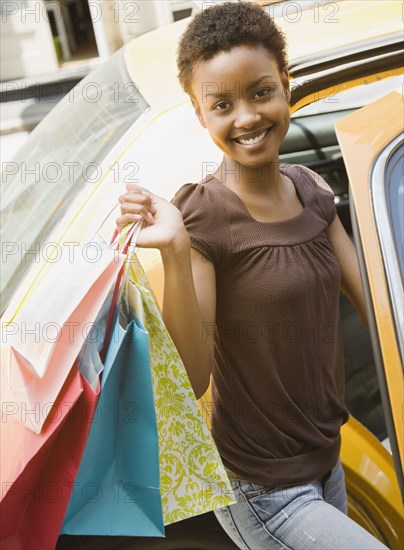 African woman entering taxi with shopping bags