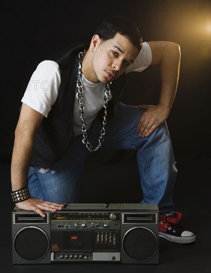 Hispanic man crouching near boom box