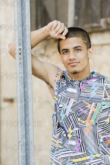 Hispanic teenage boy leaning against metal post