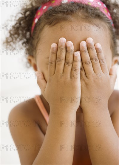 Mixed race girl covering her face