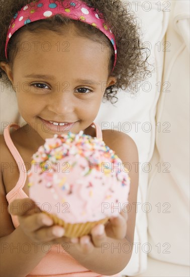 Mixed race girl holding cupcake