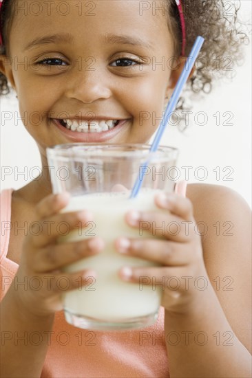 Mixed race girl holding glass of milk