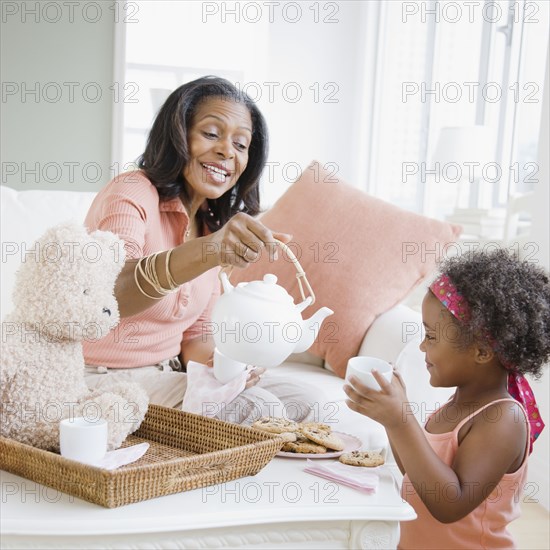 African grandmother having tea party with granddaughter