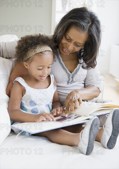 African grandmother looking a photo album with granddaughter