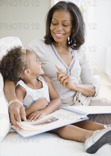 African grandmother looking a photo album with granddaughter