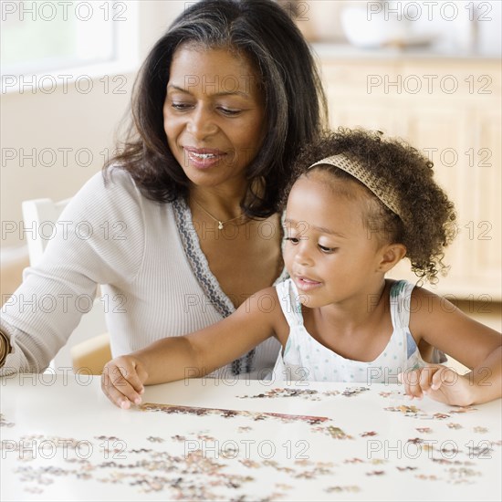 African grandmother helping granddaughter put together a puzzle