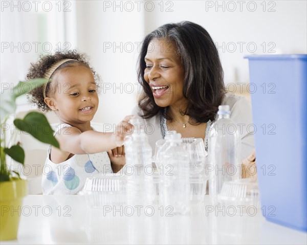 African grandmother teaching granddaughter how to recycle