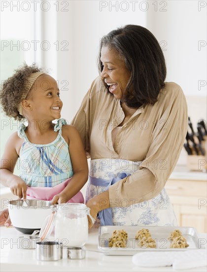 African grandmother baking cookies with granddaughter