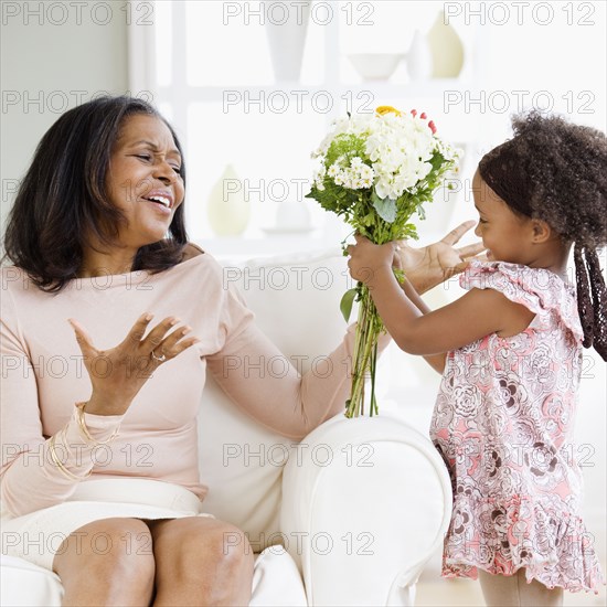 Granddaughter giving African grandmother bouquet of flowers