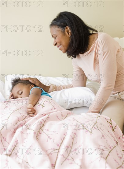 African grandmother checking on sleeping granddaughter