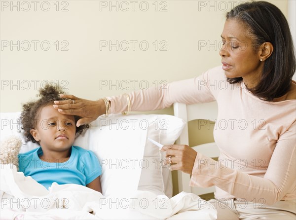 African grandmother checking granddaughter's temperature