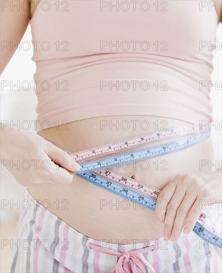 Pregnant Asian woman measuring stomach