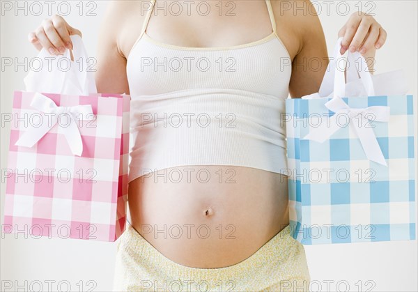 Pregnant Asian woman holding pink and blue shopping bags
