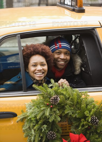 African couple riding in taxi with Christmas wreath