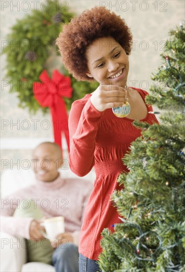 Mixed race woman placing ornament on Christmas tree