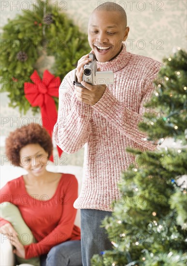 African man using video camera to film Christmas tree