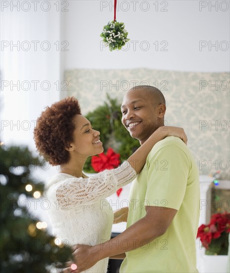 African couple kissing underneath mistletoe