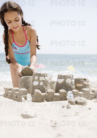 Hispanic girl building sand castle on beach