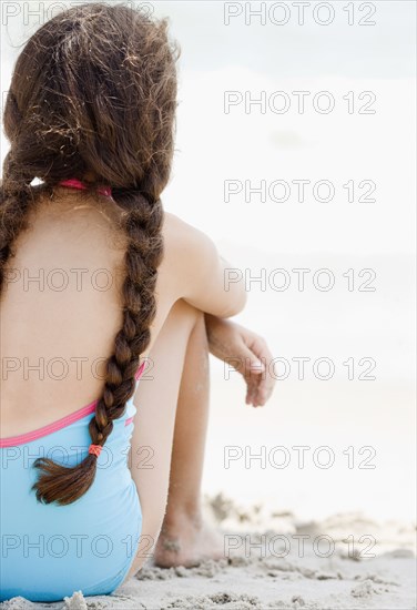 Hispanic girl sitting on beach