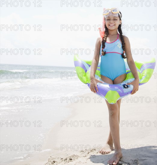 Hispanic girl with inflatable ring on beach