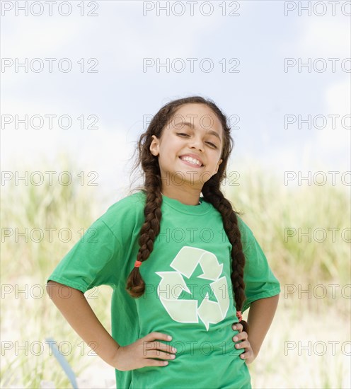 Hispanic girl on beach in t-shirt with recycling symbol