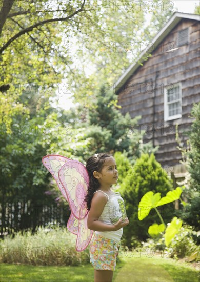 Hispanic girl in butterfly costume with jar