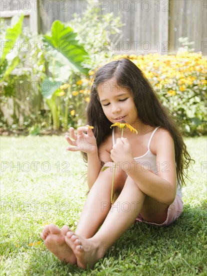 Hispanic girl picking petals off flower