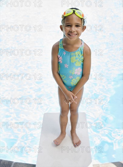 Hispanic girl in bathing suit standing on diving board