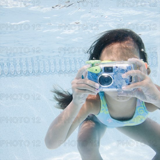 Hispanic girl taking photograph underwater