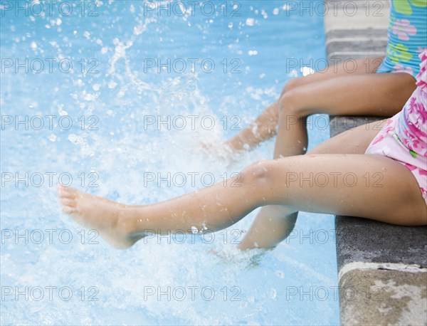 Hispanic girls splashing water in swimming pool