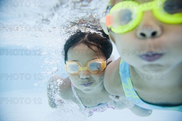 Hispanic girls swimming underwater in pool