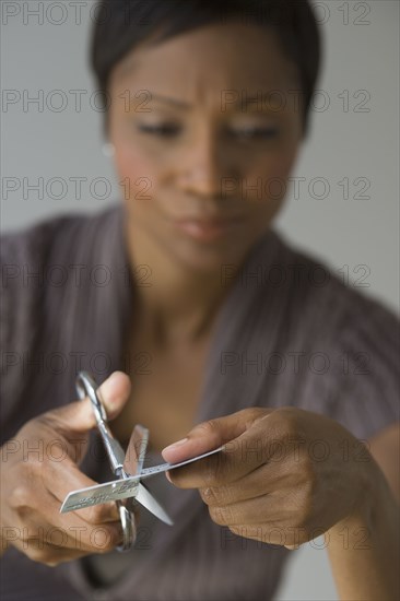 Frustrated African woman cutting up credit card