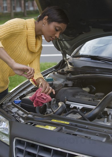 African woman checking oil in car engine