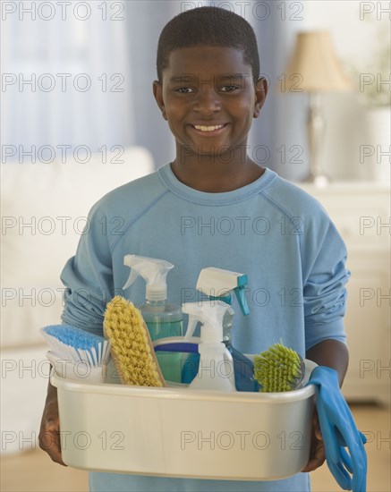 African boy holding bucket of cleaning supplies