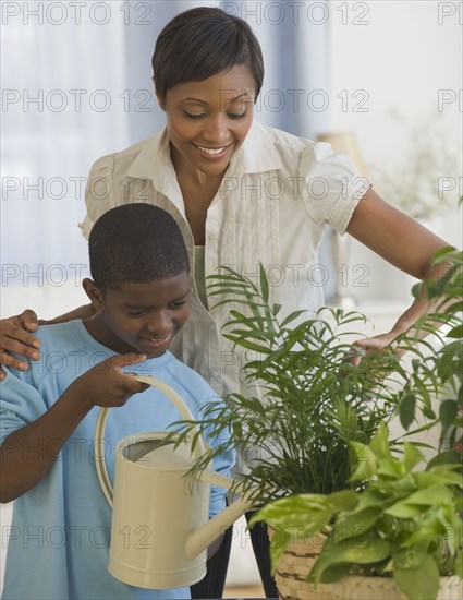 African mother and son watering plants together