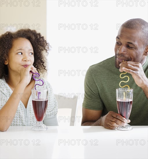 African father and daughter drinking with straws